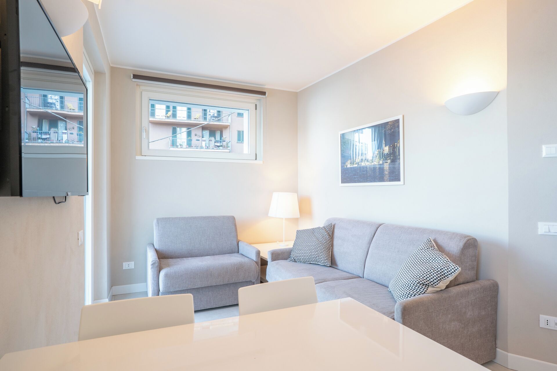 Ein modernes Wohnzimmer mit einer Couch, einem Esstisch und einem Fenster mit Blick auf Gebäude.