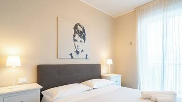 Ein Hotelzimmer mit einem Bett, zwei Nachttischen, einer Lampe und einem Fenster mit Vorhängen.