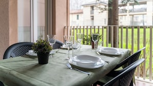 A dining table set outdoors with a green tablecloth, clear glassware, and a small potted plant. - Il Riflesso del Lago (Lecco)