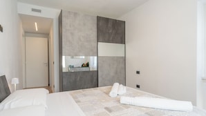 A modern bedroom with a large bed, a built-in wardrobe, and a mirror.
