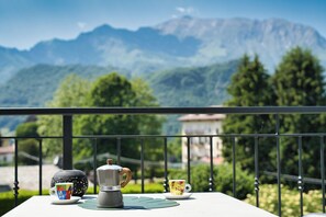 Un balcon avec une table dressée pour deux personnes, une cafetière et deux tasses.