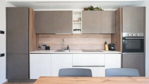 A modern kitchen with a central island, built-in appliances, and a dining area with two chairs.