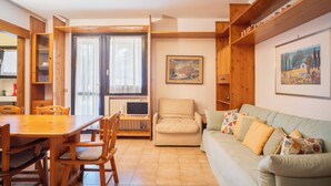 Un accogliente soggiorno con un tavolo da pranzo in legno, sedie, un divano e una televisione.
