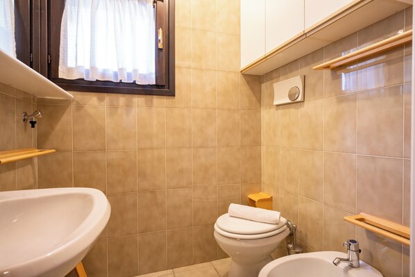 A bathroom with a sink, toilet, and bidet.