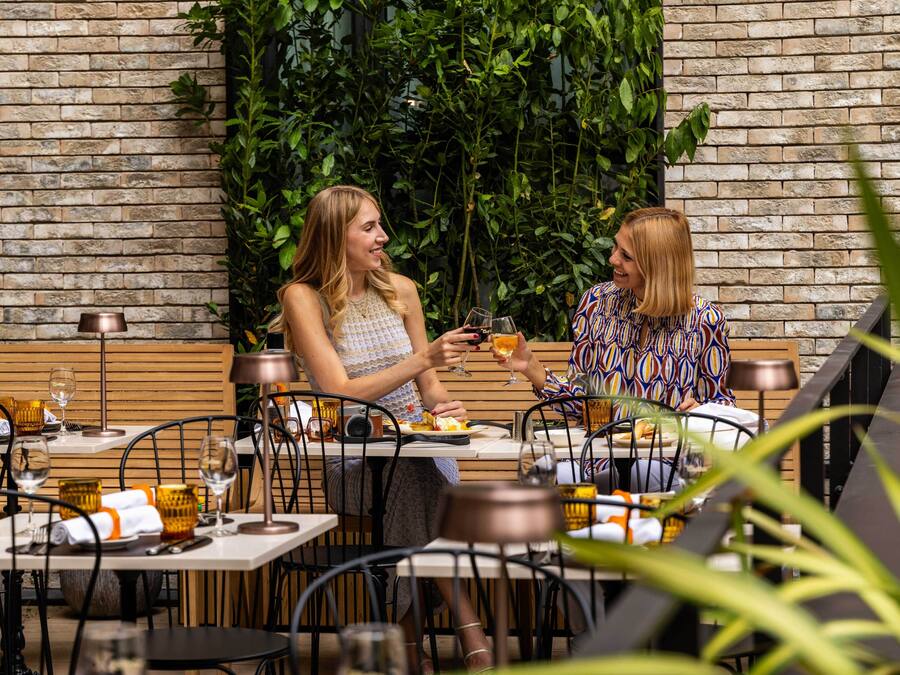Two people dining at an outdoor restaurant with brick walls and greenery.