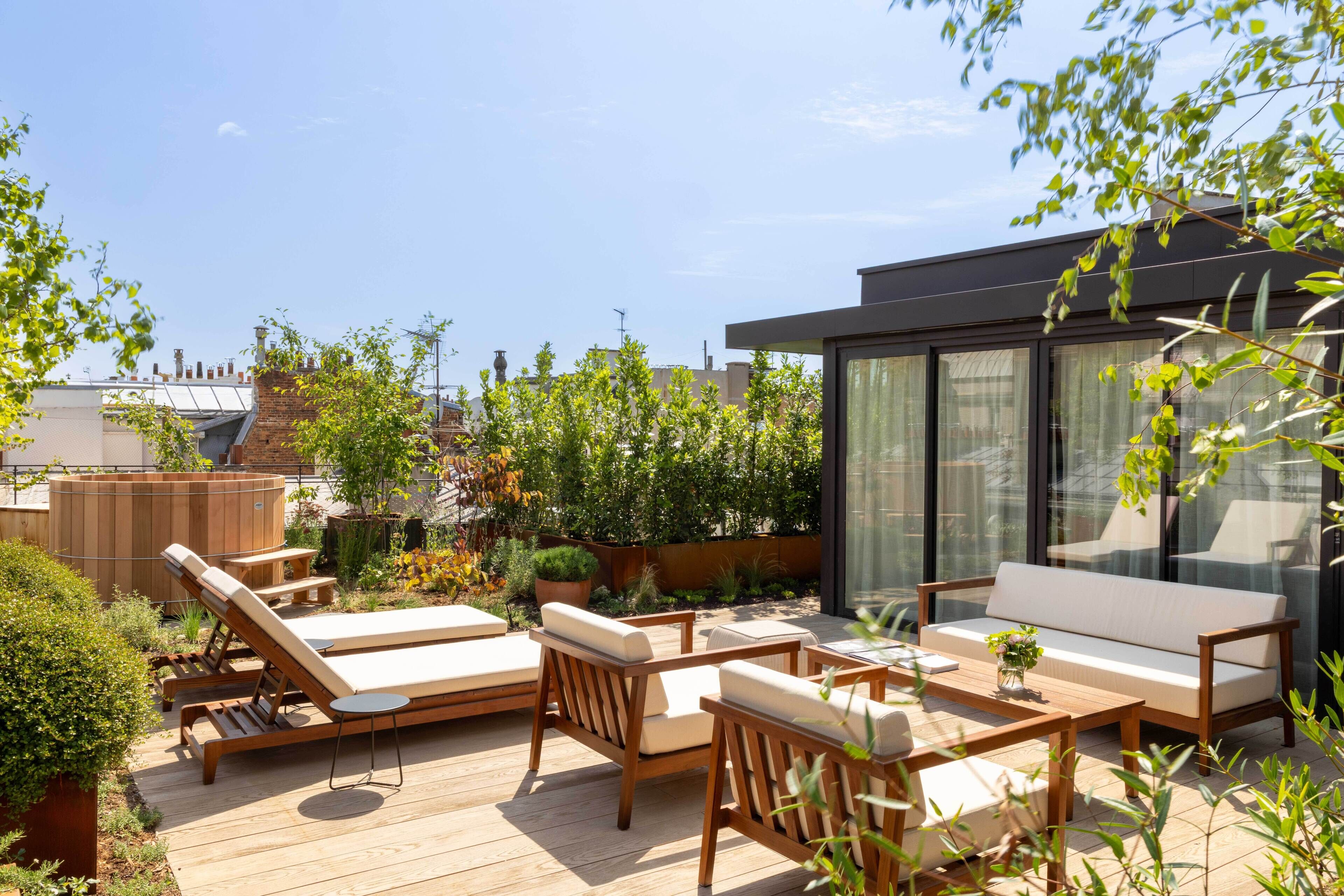 Une terrasse sur le toit, aménagée avec des fauteuils de jardin en bois, un canapé et une table.