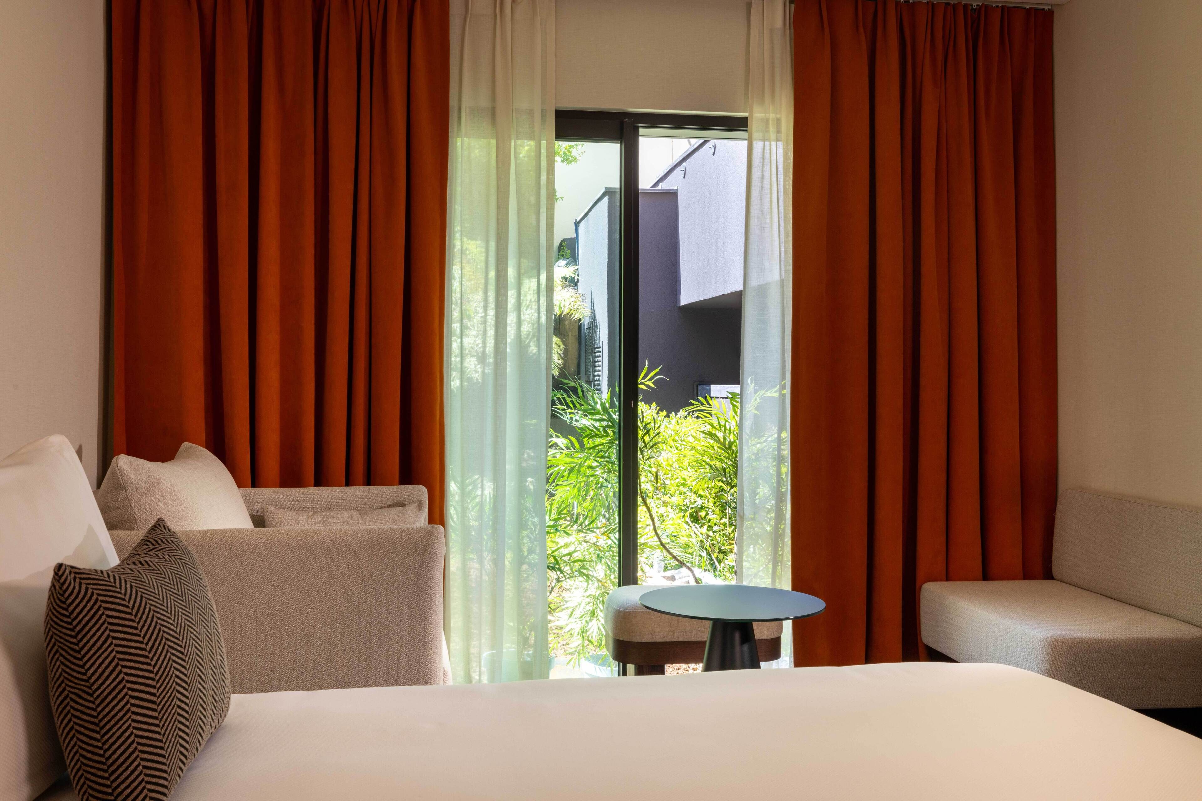 Habitación de hotel con cama, dos sofás, una mesita y vistas a zonas verdes.