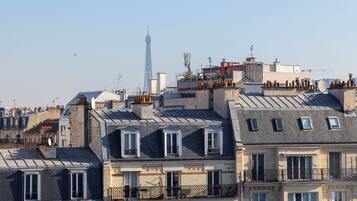 Un immeuble à plusieurs étages, doté de balcons, d’où l’on peut admirer la Tour Eiffel en arrière-plan.