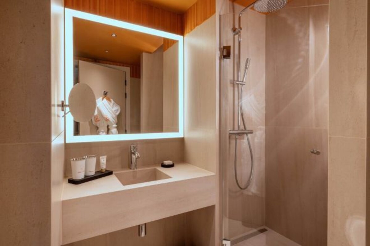 A modern bathroom with a large mirror, a sink, and a shower.