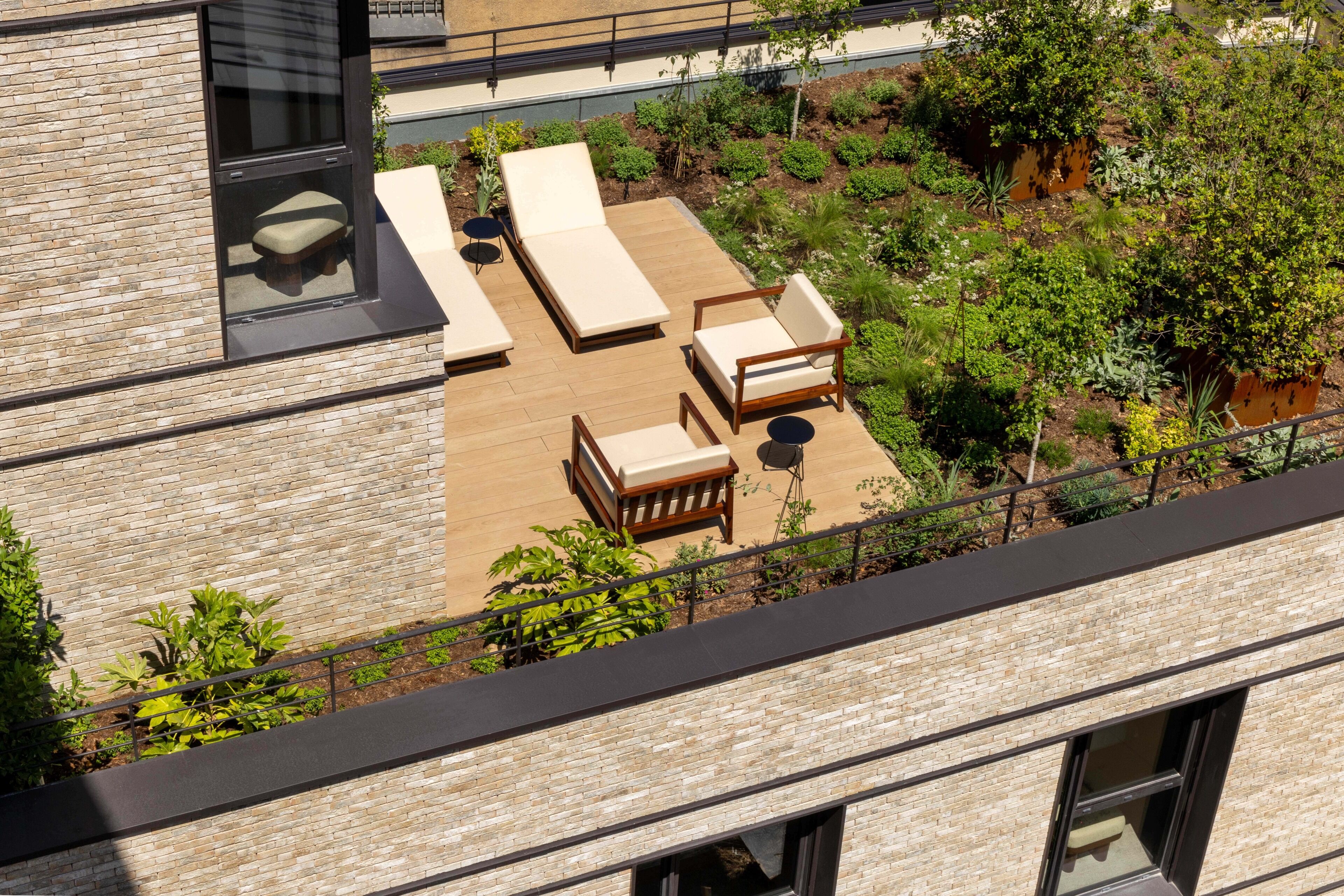 A rooftop terrace with lounge chairs, a wooden table, and a small seating area.