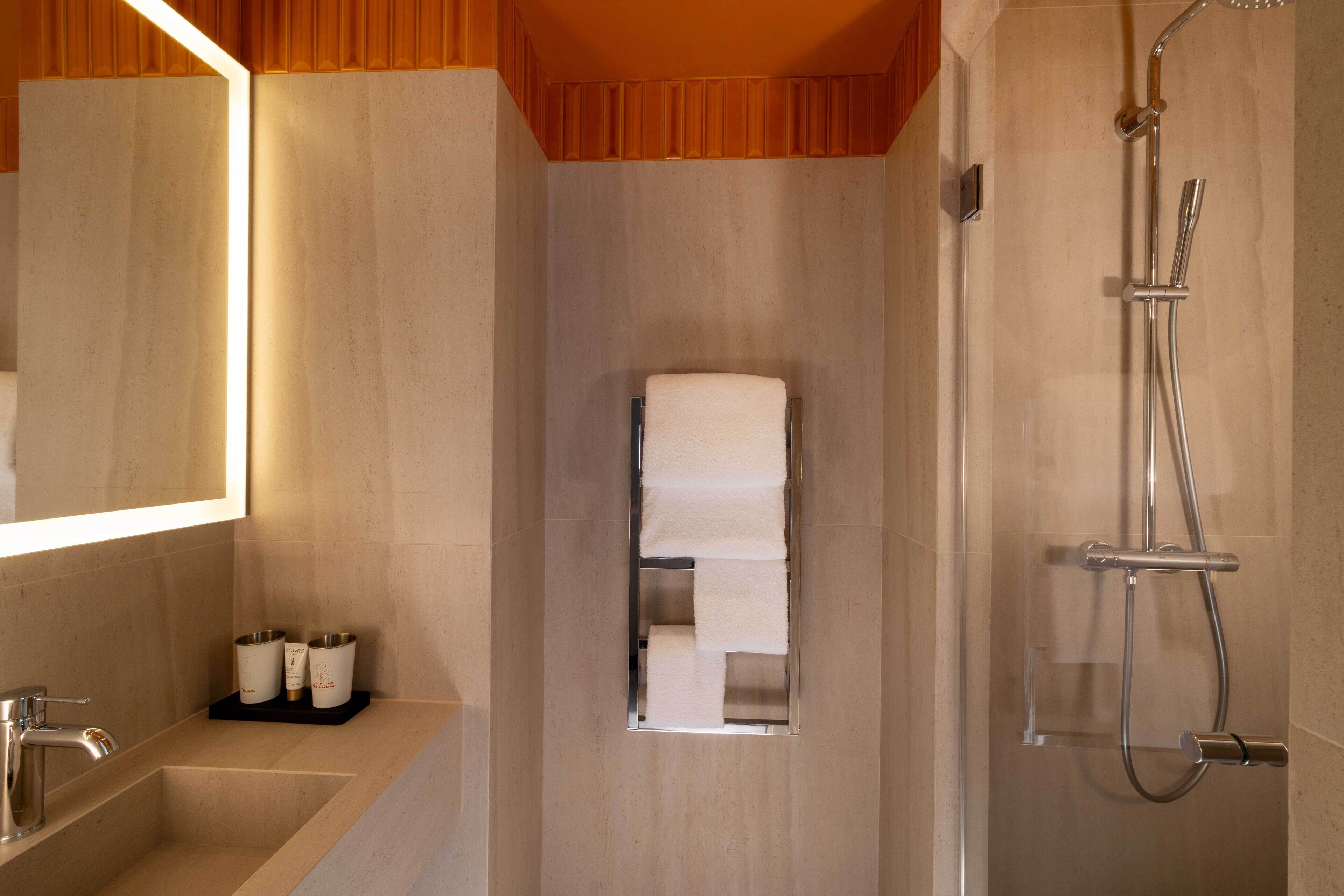 Un baño moderno con ducha integrada, lavamanos con espejo y un perchero para toallas.