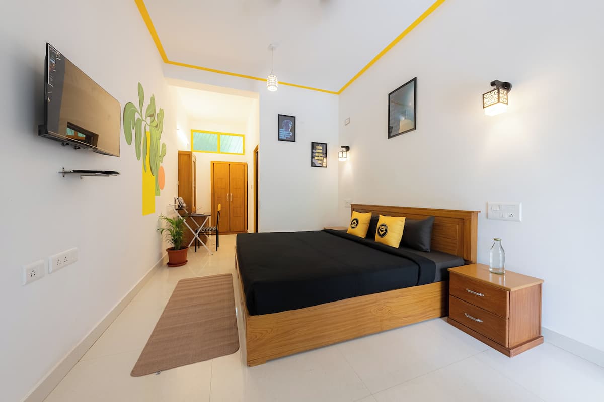 A modern bedroom with a wooden bed, bedside tables, a TV, and a potted plant.