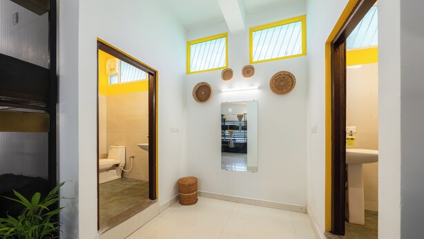 Un couloir avec des toilettes, un miroir et une plante en pot.