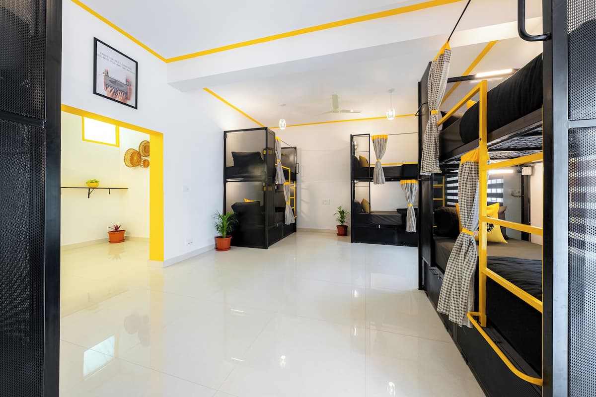 A modern, well-lit room with bunk beds, a small kitchenette, and a clean, tiled floor.