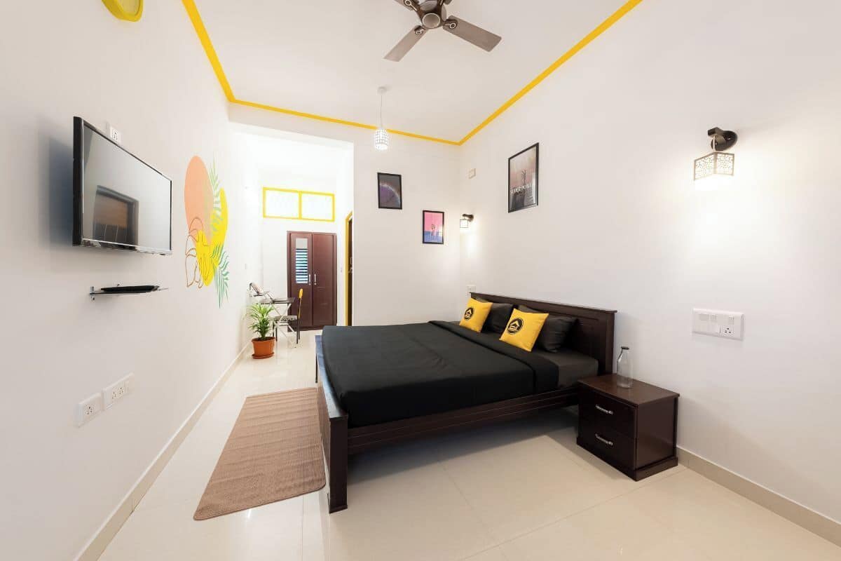 A modern bedroom with a bed, bedside table, and a TV mounted on the wall.