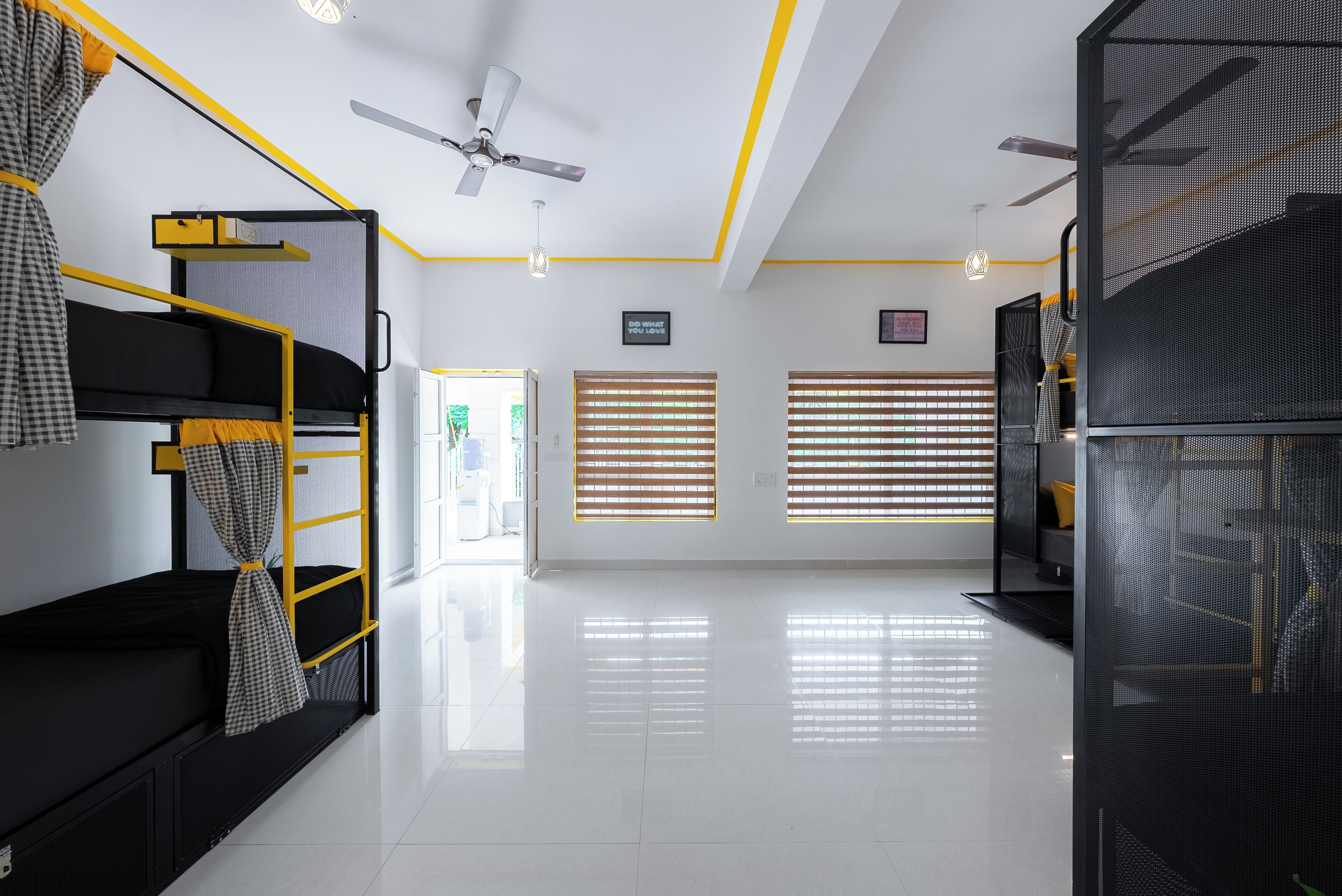 Una habitación de hotel moderna con literas, ventilador de techo y un ventanal con persianas.