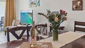 Une table à manger avec une bouteille de vin, deux verres et un arrangement floral.