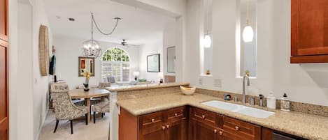Una cocina moderna con encimeras de granito, armarios de madera y un ventanal grande.