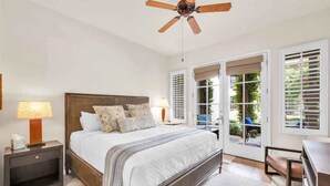 A bedroom with a large bed, a ceiling fan, and a view of the outdoors through a sliding glass door. - Desert Charm A | 1BR Legacy Villa (La Quinta)