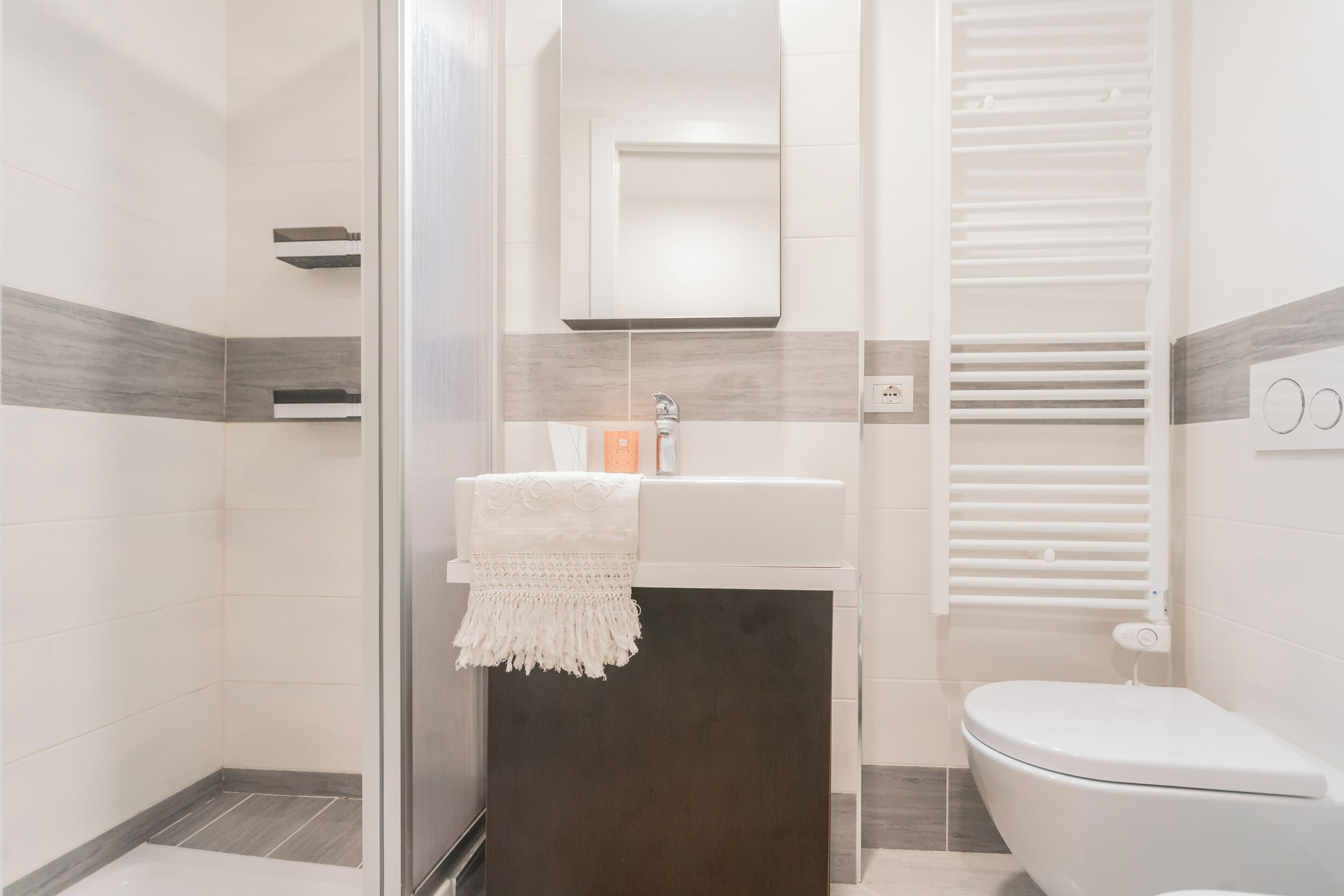 Un baño moderno con ducha, lavamanos con toalla y retrete.