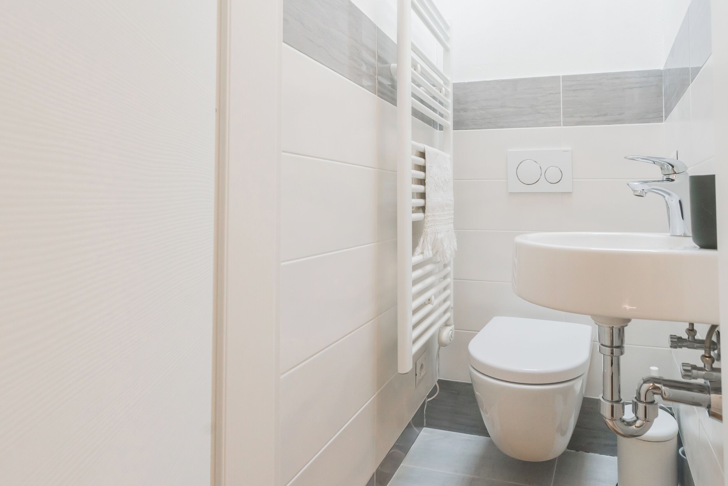 A modern bathroom with a white toilet, a sink, and a towel rack.