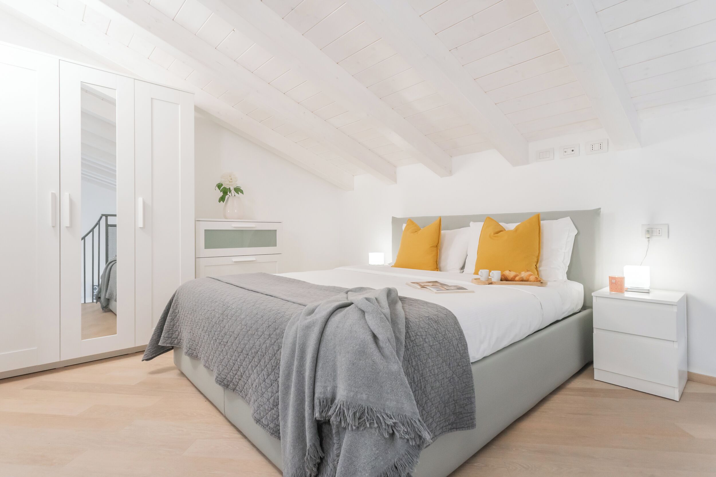 Une chambre moderne avec un grand lit, une armoire blanche et une petite table de chevet.
