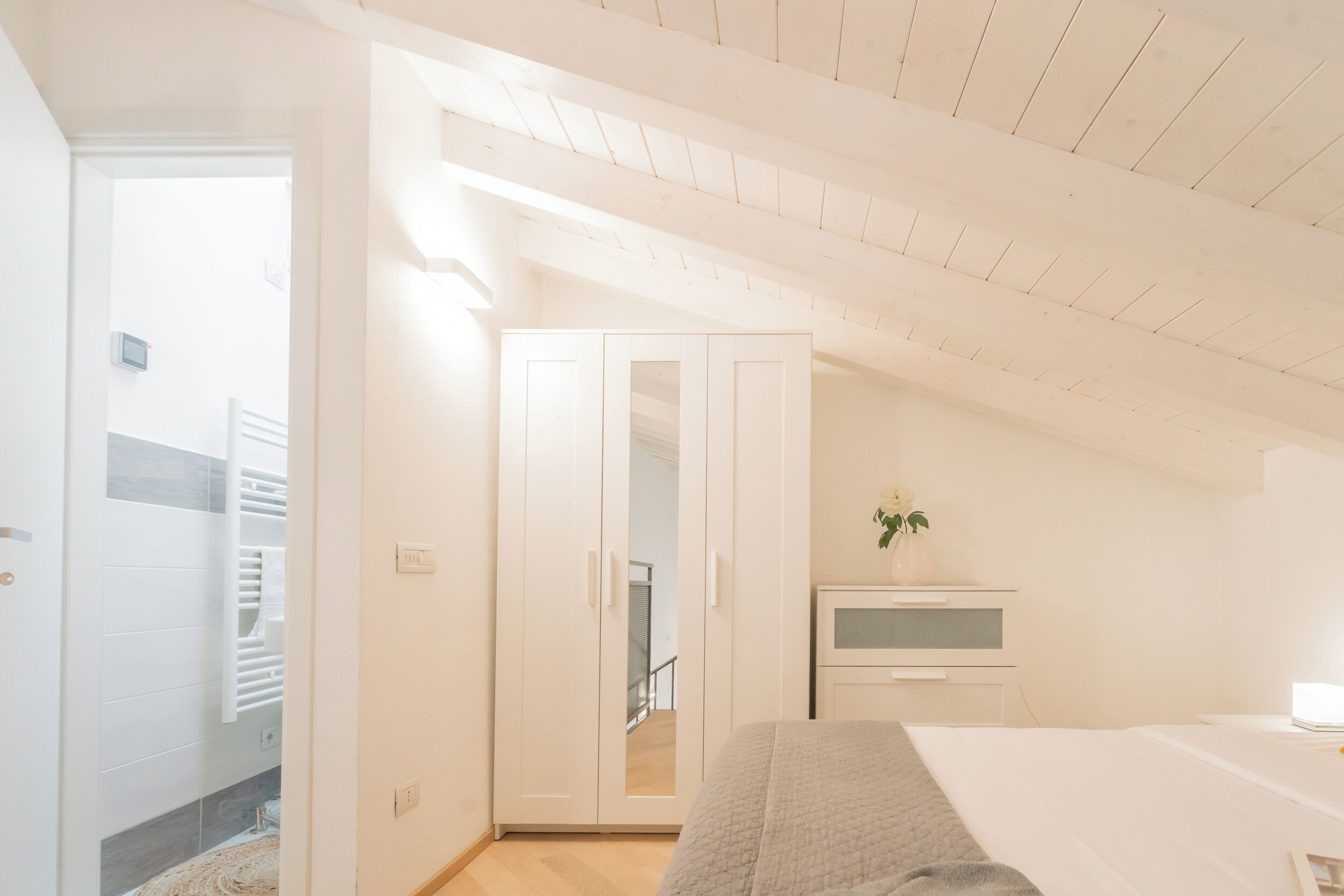 Ein Schlafzimmer mit Bett, Kleiderschrank, Nachttisch und einer kleinen Topfpflanze.