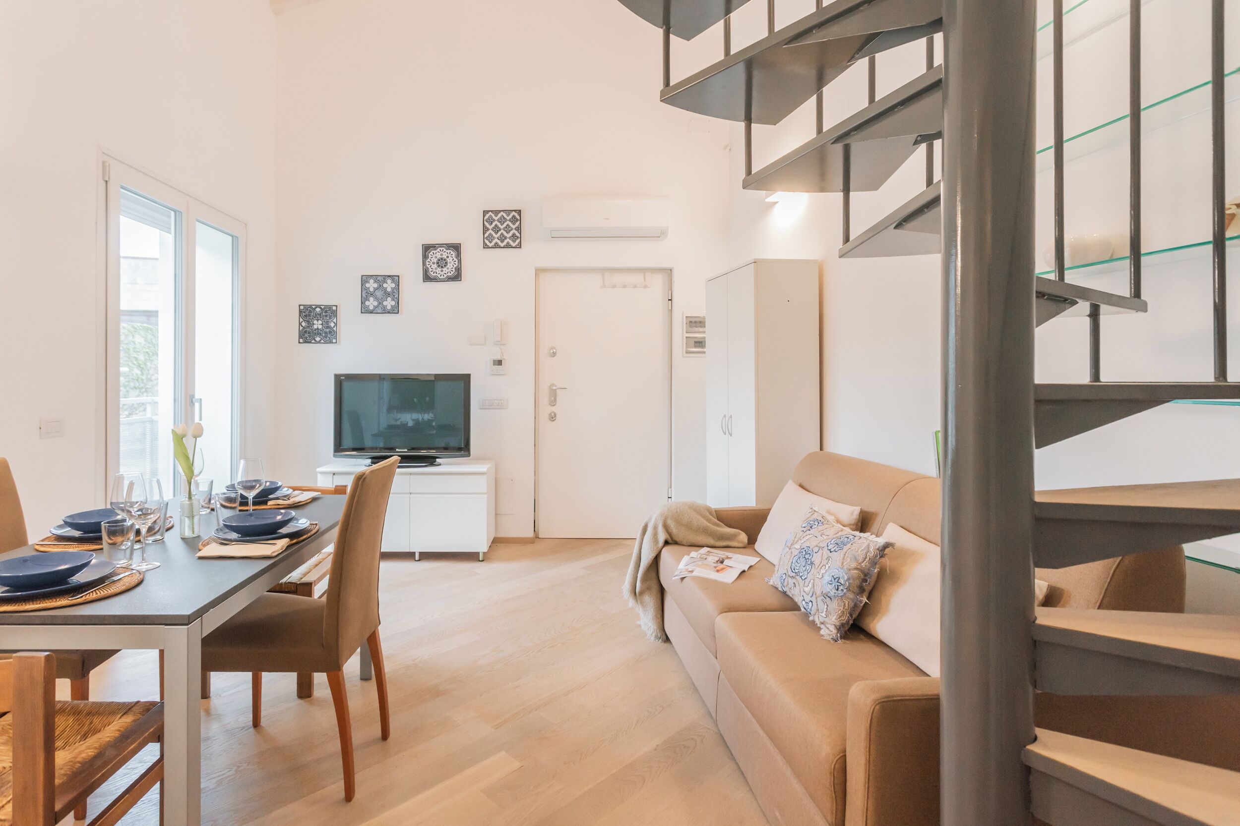 Un salon moderne comprenant un coin repas, un canapé, un téléviseur et un escalier.