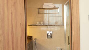 A bathroom with a toilet, shower, and glass-enclosed shower stall.