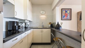 Una cocina moderna con armarios blancos, encimera negra, un fregadero y un reloj en la pared.