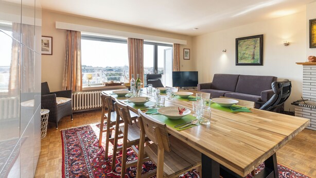 Una sala de estar moderna con comedor, ventanas grandes y vistas a la ciudad.
