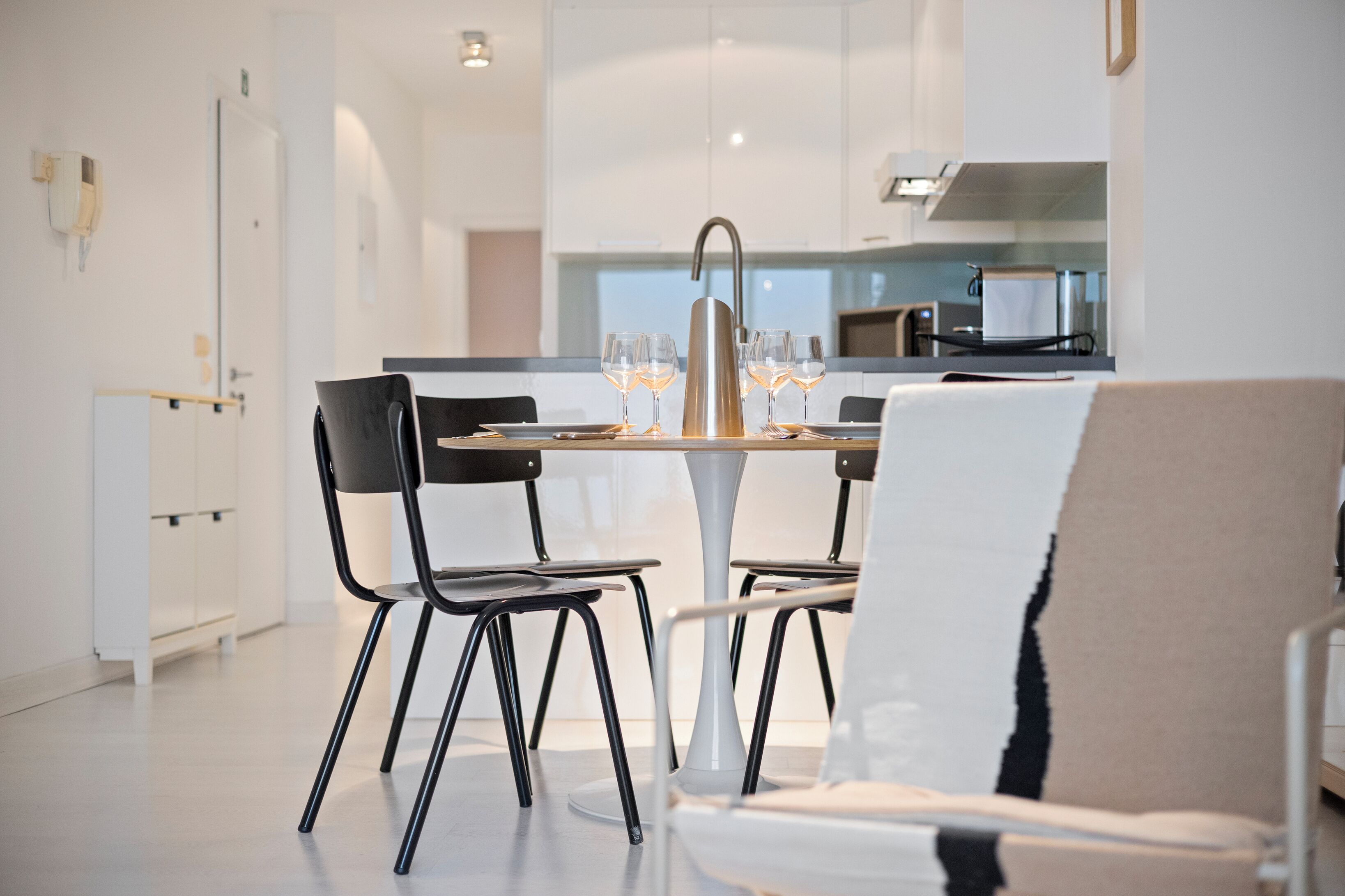 A modern dining area with a white table, black chairs, and a central light fixture.