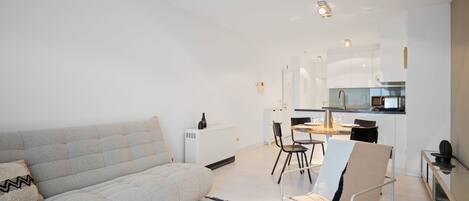 Ein modernes Wohnzimmer mit einer Couch, einem Couchtisch und einem Essbereich mit Stühlen und einem Tisch.