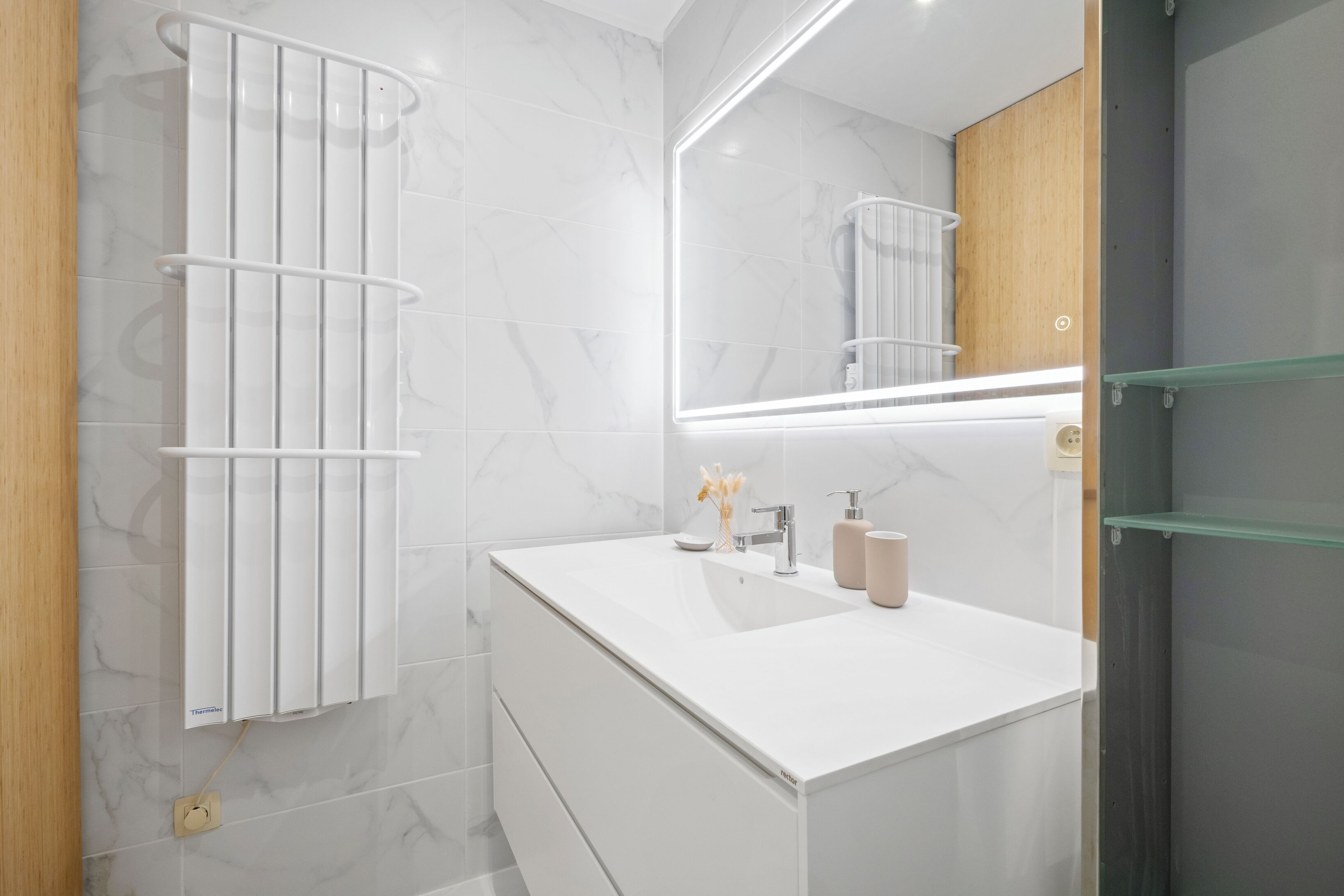 Un baño moderno con un tocador blanco, un espejo y un perchero para toallas.