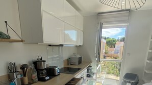 A modern kitchen with white cabinets, a wooden countertop, and a view of the outdoors. - Le Refuge du Plongeur - New & Cosy Apartment (Saint-Mandrier-sur-Mer)