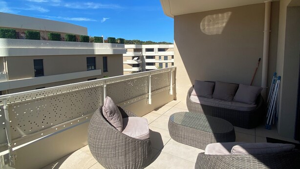A balcony with wicker furniture, a view of buildings, and a clear sky. - Le Refuge du Plongeur - New & Cosy Apartment (Saint-Mandrier-sur-Mer)