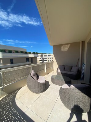 A balcony with wicker furniture, a view of buildings, and a clear sky. - Le Refuge du Plongeur - New & Cosy Apartment (Saint-Mandrier-sur-Mer)