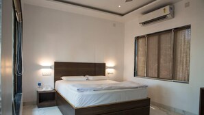 Een moderne hotelkamer met een groot bed, bedlampen, een airconditioning en een raam met verticale jaloezieën.