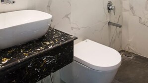 Een badkamer met een witte marmeren wand, een witte wastafel en een toilet.