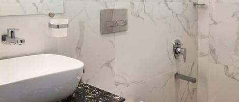 A bathroom with a white marble wall, a white sink, and a toilet.