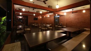 Een restaurant met houten tafels en stoelen, plafondventilatoren en hanglampen.