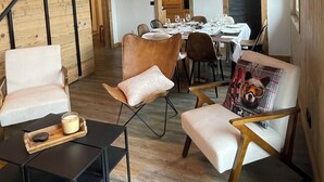 Comedor con paredes y techo de madera, una mesa dispuesta para comer y sillas modernas.