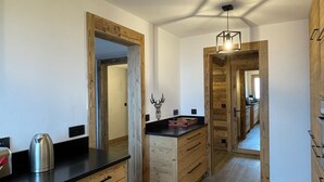 Una cocina moderna con armarios de madera, encimera negra y una lámpara colgante.
