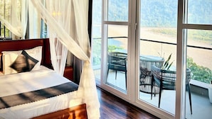 Une chambre à coucher avec un grand lit, un baldaquin et une vue sur un balcon aménagé avec du mobilier d’extérieur.
