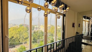 Un intérieur moderne avec de grandes fenêtres, un balcon doté d’une balustrade et des luminaires sphériques suspendus.