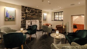 A cozy lounge area with stone walls, comfortable seating, and ambient lighting. - Suites at Derby House (Castletown)