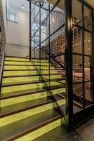 Una escalera con barandillas de cristal que conduce a una habitación con una estantería para vinos.