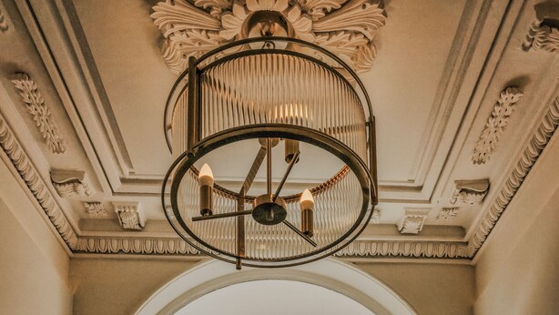 A grand entrance with a black door, ornate ceiling, and a view of a castle through an archway. - Suites at Derby House (Castletown)