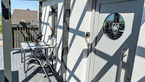 An outdoor patio with a table and chairs, a wooden pergola, and a door with a heart-shaped window. - Cosy apartment for 2 people with WIFI, TV and terrace (Schieder-schwalenberg)