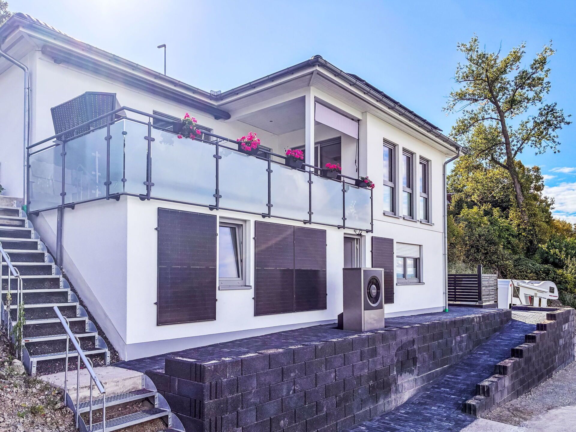 A modern two-story house with a balcony, a staircase, and a large window.